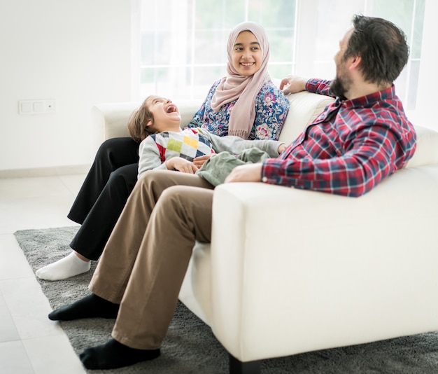 Happy Muslim family sitting on sofa in living roome at home