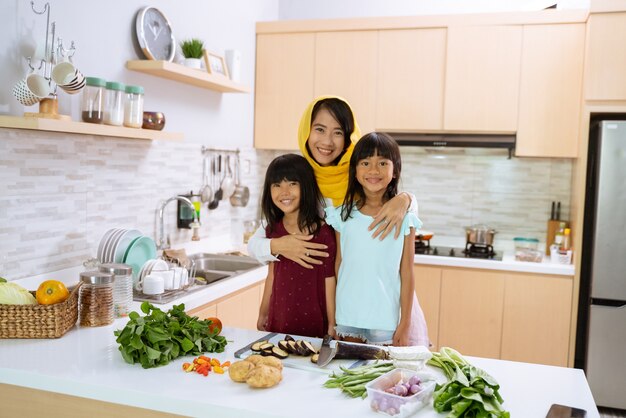 Счастливая мусульманская мать с двумя прекрасными дочками вместе готовит на кухне