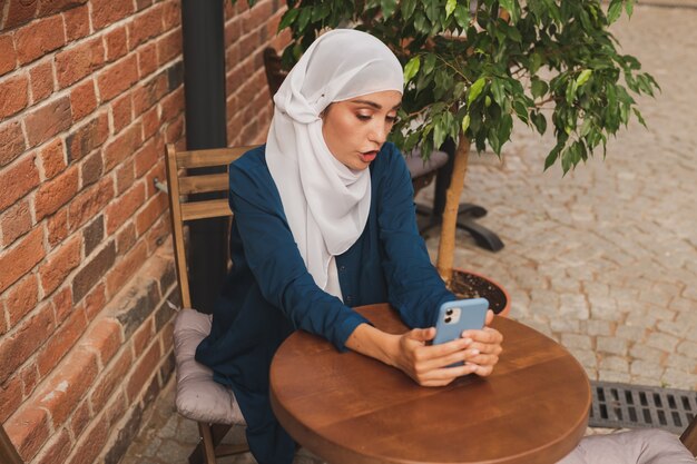 Photo happy muslim woman having video call on smartphone in city