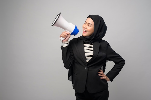 Happy muslim woman is announcing with megaphone on white background