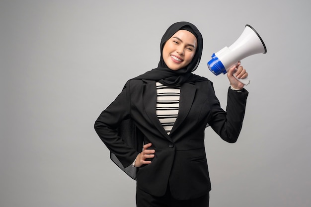 Happy muslim woman is announcing with megaphone on white background