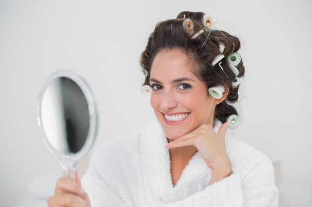 Happy natural brunette holding hand mirror