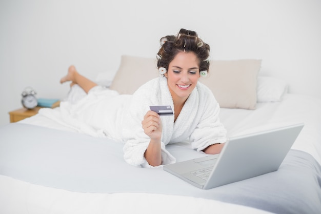 Happy natural brunette using credit card and laptop