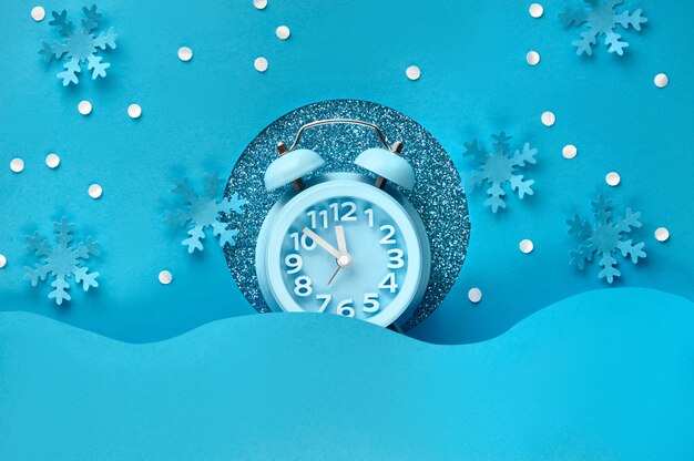 Happy New Year 2020! Alarm clock in paper hole, flat lay on blue color paper