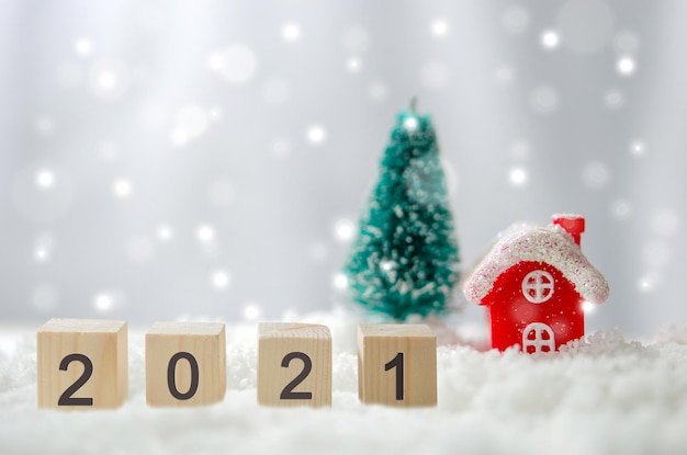 Happy New Year 2021 creative ideas at cubes on snow and background Red house and Christmas tree
