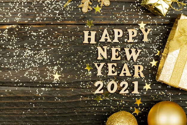 Photo happy new year 2021 text on wooden surrounded golden christmas toys.