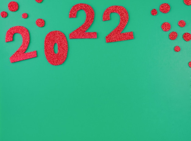 Happy new year 2022 background new year holiday card on green background bright red numbers.