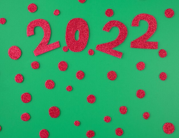 Happy new year 2022 background new year holiday card Shiny red numbers and candies on a green