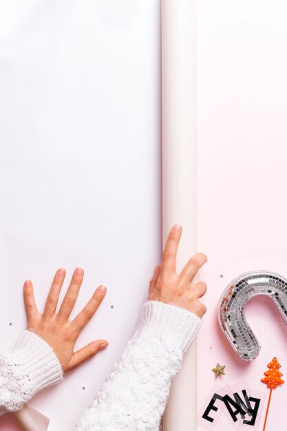 Happy New Year 2022 Female hands on a pink background decorated with Christmas ornaments nearby