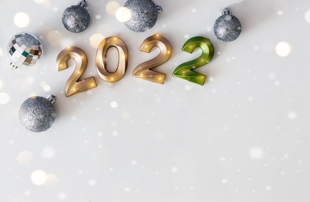 Felice anno nuovo 2022 concetto di vacanza, numeri d'oro 2022, palle di natale d'argento con bokeh e spazio di copia