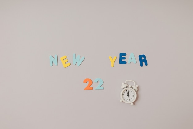 2022년 새해 복 많이 받으세요. 회색과 보라색 배경에 화려한 양초와 거품 스티커 문자가 있습니다. 복사 공간, 평평한 위치.