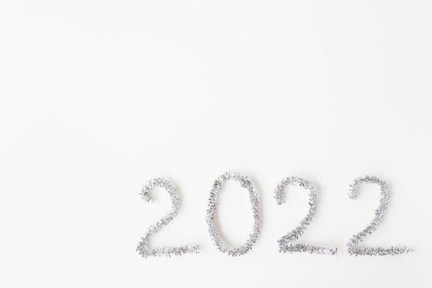 Photo happy new year 2022 written in foil and new year rain on an isolated white background. happy new year greetings.