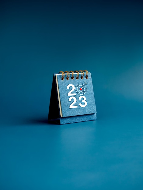 Happy new year 2023 background 2023 numbers year with target icon on blue small desk calendar cover standing on blue background vertical style Business goals and success concepts