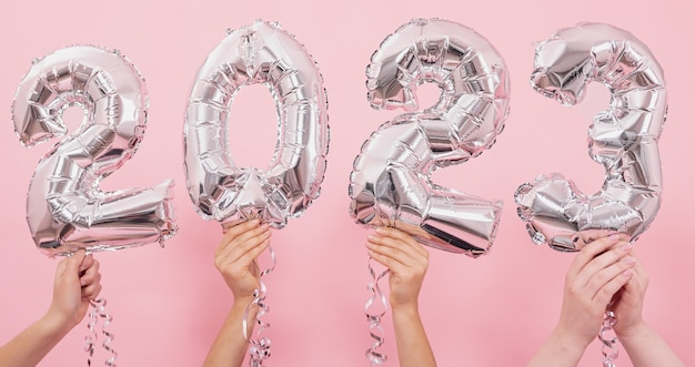 Foto celebrazione del buon anno 2023. palloncini in lamina d'argento numero 2023 su sfondo rosa.