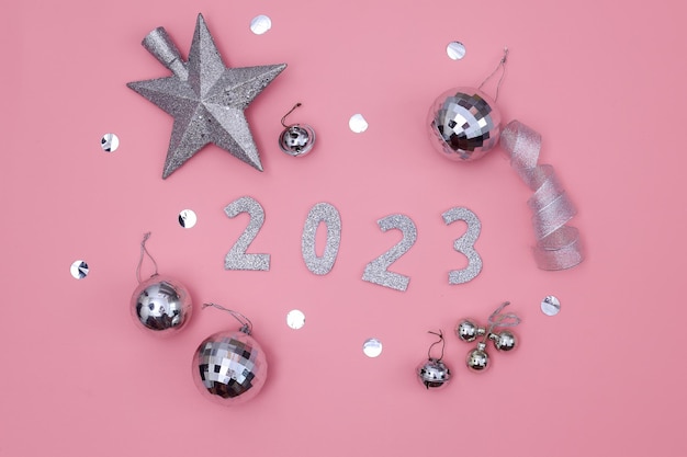 사진 2023년 새해 복 많이 받으세요. 분홍색 배경에 반짝이는 축제 장식이 있는 은색 숫자