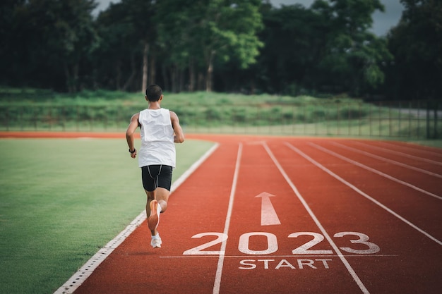 Happy new year 2023 Sport man runner running into the new year 2023 Start up of runner man jogging at stadium go to Goal of Success People running as part of Number 2023 Sport health care