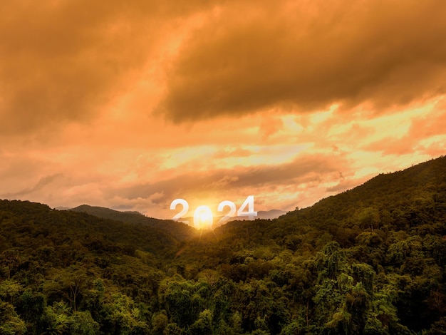 Foto felice anno nuovo 2024 con lettere sul verde lussureggiante delle montagne fertili e sul cielo dorato del tramonto con una scena straordinaria concetti di successo e destinazione benvenuti a buon natale e felice anno nuovo nel 2024