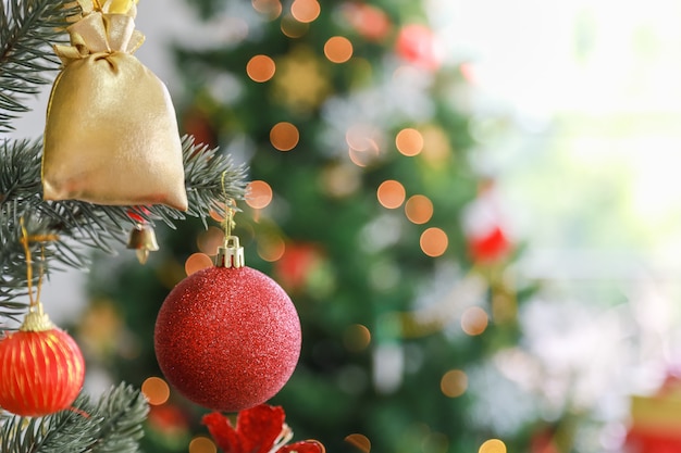 Happy New Year and Christmas Concept. Close up of shiny red ornament ball and accessories on Xmas tree with bokeh with copy space for text.