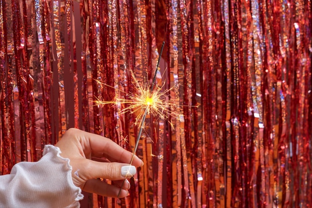 輝きのお祭りの背景にベンガルの火で女性の手で幸せな新年のコンセプト