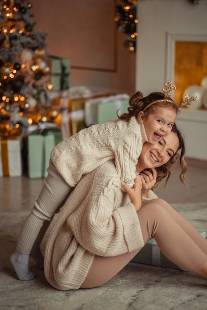 新年あけましておめでとうございます家族の伝統若い母親と娘は、家でクリスマス ツリーと暖炉のそばで楽しんでいます。