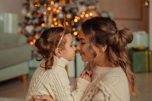 새해 복 많이 받으세요 가족 전통 젊은 어머니와 그녀의 딸은 크리스마스 트리와 벽난로 근처에서 집에서 즐거운 시간을 보냅니다.