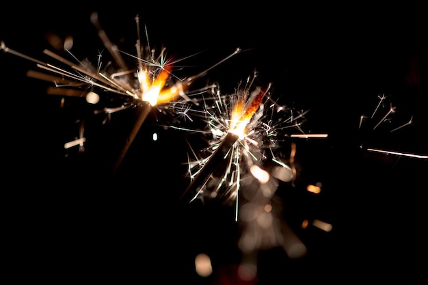 Happy New Year Glittering burning sparkler against black night background