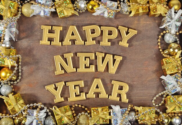 Photo happy new year golden text and christmas decorations on a wooden background