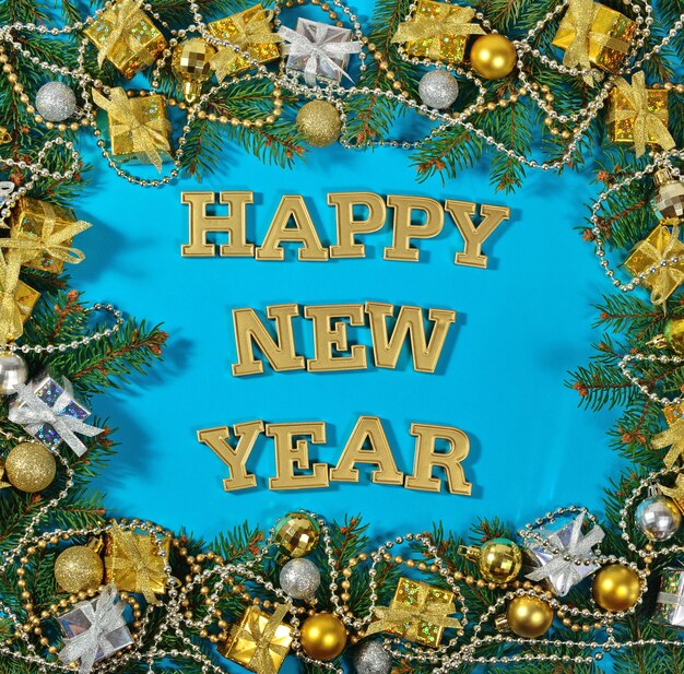 Happy New Year golden text and spruce branch and Christmas decorations on a blue background