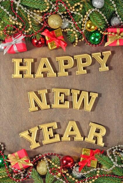 Happy New Year golden text and spruce branch and Christmas decorations on a wooden background