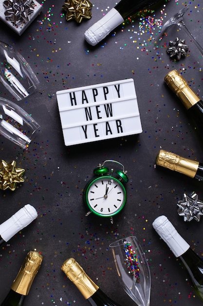 Cartolina d'auguri di felice anno nuovo bicchieri di champagne e coriandoli di bottiglie