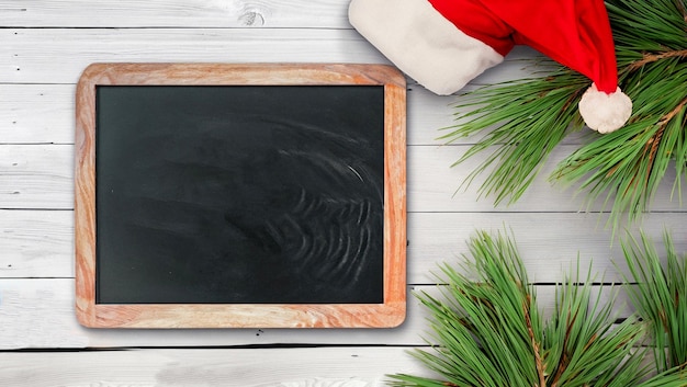 happy new year holiday greeting cardChalkboard pine branches and santa hat on rustic white wooden