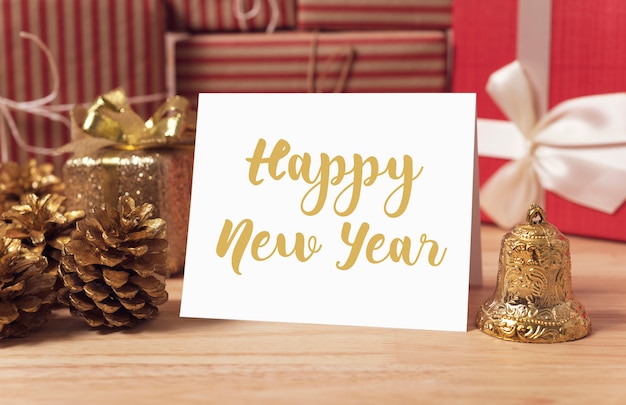 Photo happy new year holiday greeting paper card design mockup with decoration on wood table.