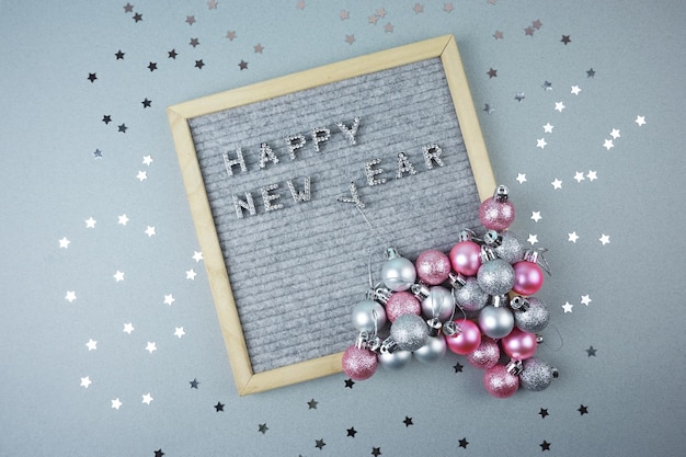 The happy new year inscription is laid out on a gray background decorated with silver stars