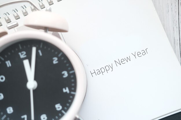Foto testo di felice anno nuovo sul calendario con l'orologio sul tavolo