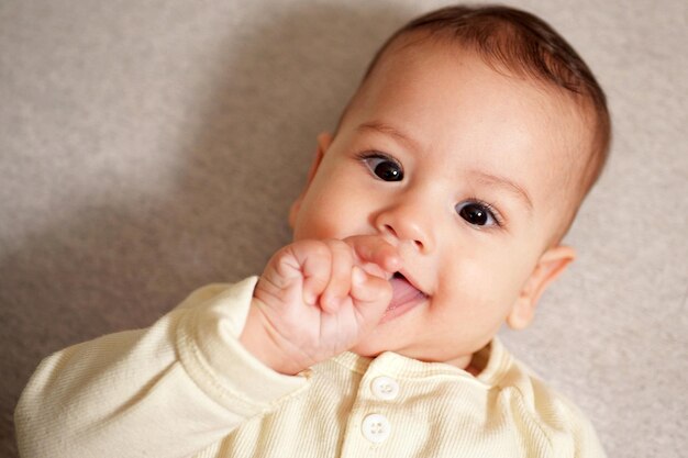 Happy newborn baby makes a funny face Portrait of a crawling baby in his room close up