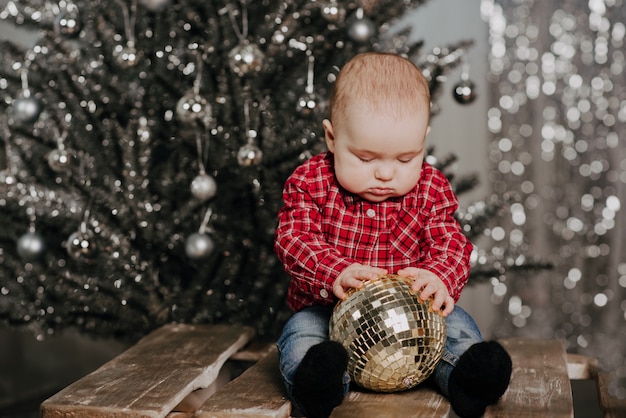 クリスマスの装飾の座っている幸せな新生児の少年