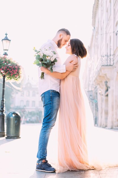 Happy newlywed couple hugging and laughing on city streets