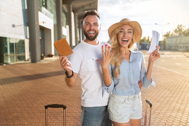 Happy newlyweds going on honeymoon and holding tickets