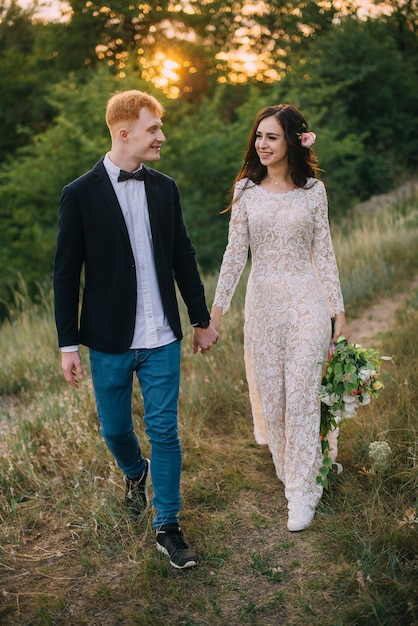 Happy newlyweds holding hands and walking in nature