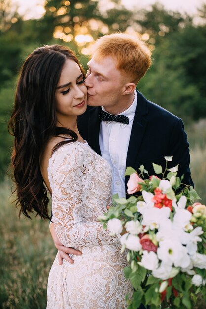 Happy newlyweds kissing at sunset