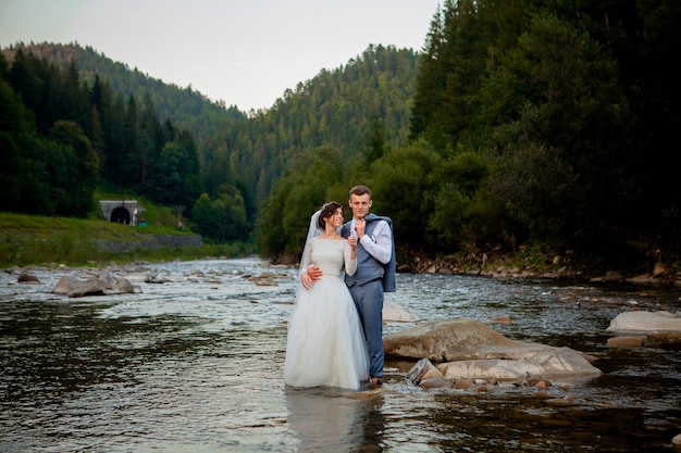 川に立って笑っている幸せな新婚夫婦