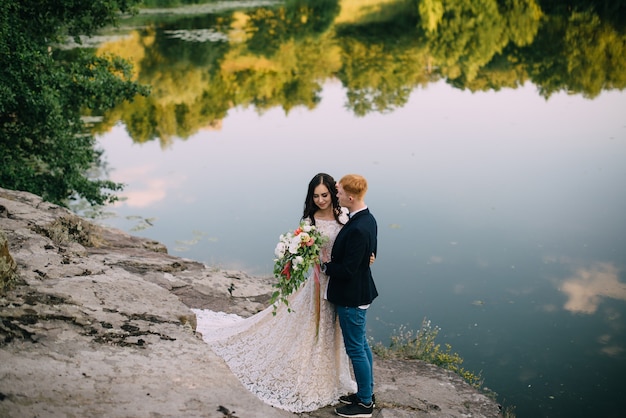 Happy newlyweds standing and smiling on the river bank