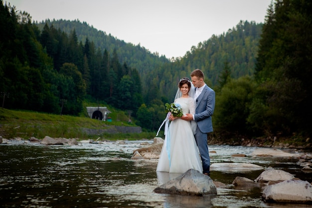 川に立って笑っている幸せな新婚夫婦。新婚旅行者、バレンタインデーの写真。