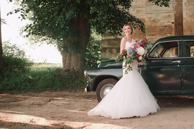 Happy newlyweds standing next to a stylish car during the walk