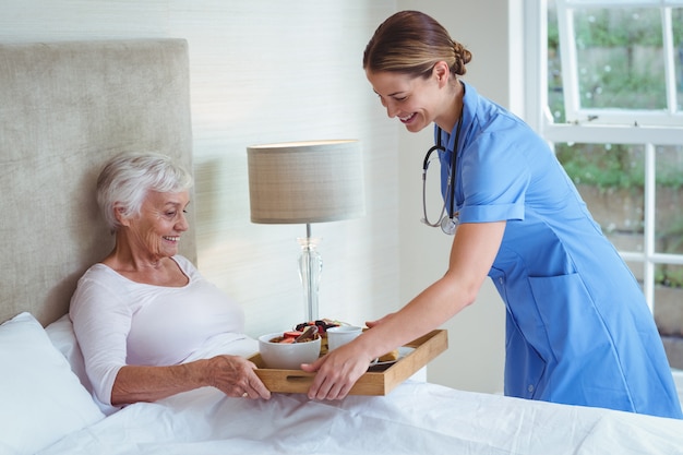 Happy nurse giving food to senior woman 