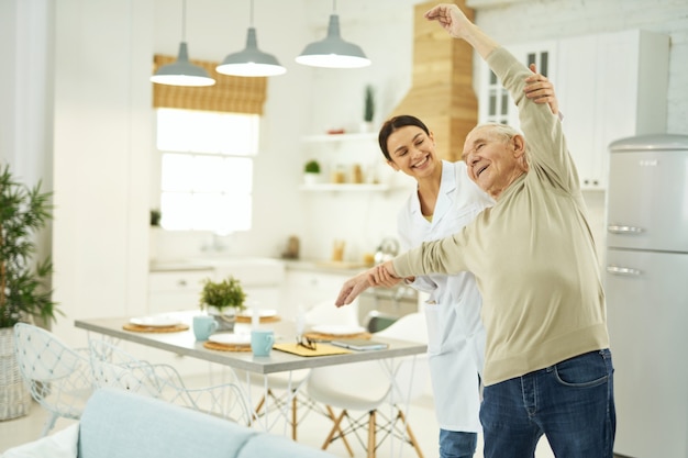 Photo happy nurse and senior citizen standing in the living room