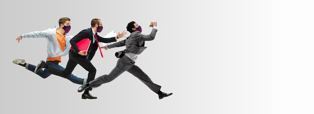 Счастливые офисные работники в масках прыгают и танцуют в повседневной одежде или костюме, изолированном на фоне студии. Бизнес, запуск, профилактика COVID, концепция движения и действий. Творческий коллаж.