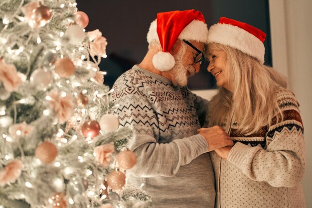 The happy old couple standing near the christmas tree