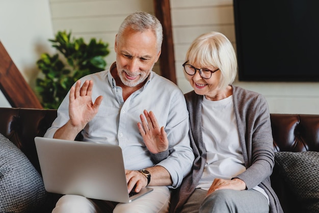 Happy old family couple waving hands looking at laptop screen
doing distance video chat calling