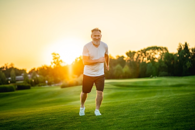 The happy old man running on the grass